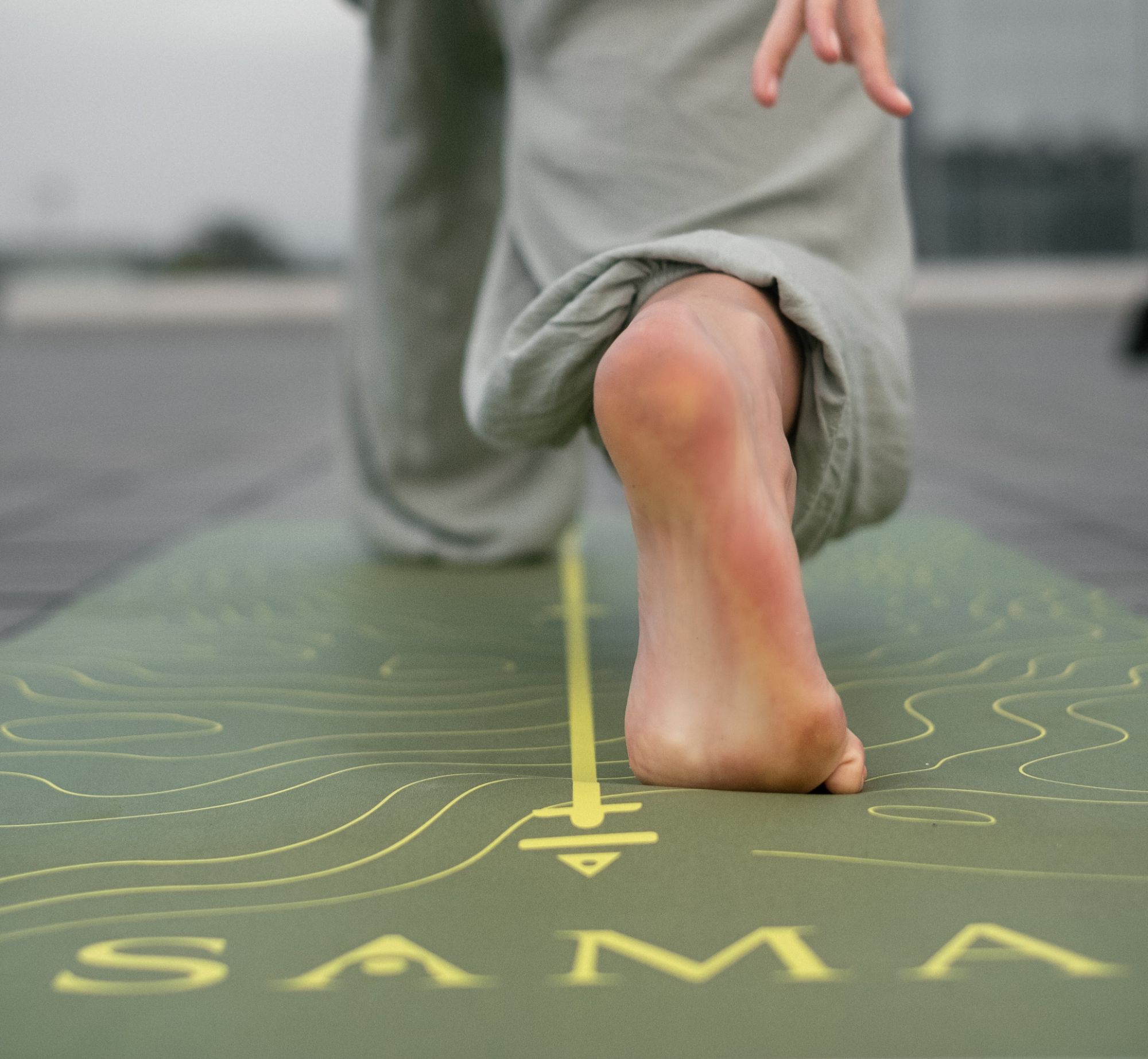 Barefoot step onto a SAMA yoga mat with a contour-line design